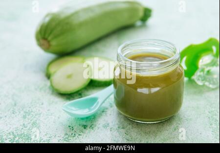 Jar with healthy baby food and zucchini on table Stock Photo