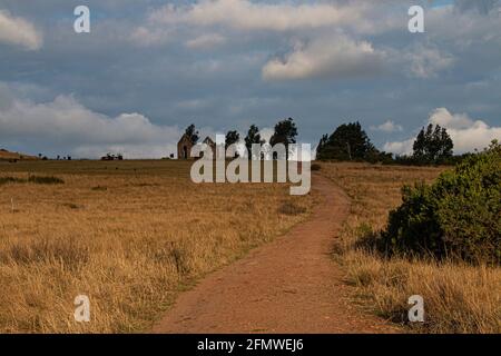 Dirt road leading up to abandoned farm building Stock Photo