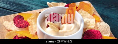 Vegetable chips with a dip panorama on a dark blue wooden background Stock Photo