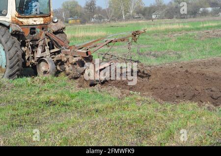 Spring soil preparation. A close-up on a tractor plowing and tilling the field, soil before sowing or planting vegetables. Stock Photo