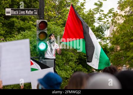 Washington, DC, USA, 11 May, 2021.  Pictured: A man waves a Palestinian flag from a traffic light near the White House during protest calling for the United States to stop funding apartheid, occupation, and violence in Palestine.  The street sign for the recently-closed Black Lives Matter Plaza remains in place.  Credit: Allison C Bailey / Alamy Live News Stock Photo