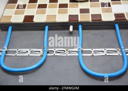 Electric floor heating installation: A close-up on an electric radiant floor heating covered with mosaic tiles in a bathroom. Stock Photo