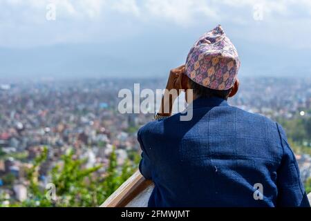 Nepali man wearing a topi contemplates Kathmandu city from Swayambhunath, in Nepal. Stock Photo