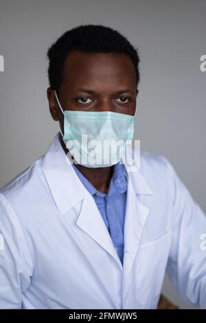 Young black man wearing a white coat and face mask Stock Photo