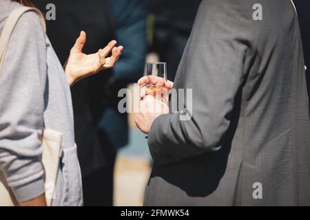 Details with a man and a woman interacting at a classy event, while holding a glass of wine. Stock Photo
