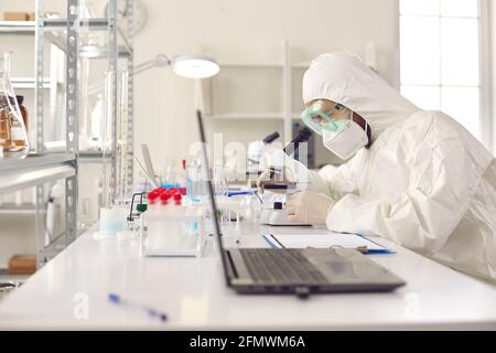 Unrecognizable scientist pharmacologist in protective uniform at laboratory Stock Photo