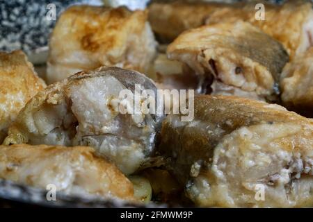 Cooking white sea fish hake. Baked hake or pollock with golden crust are preparation on domestic kitchen. Selective focus. Close-up. Indoors. Stock Photo