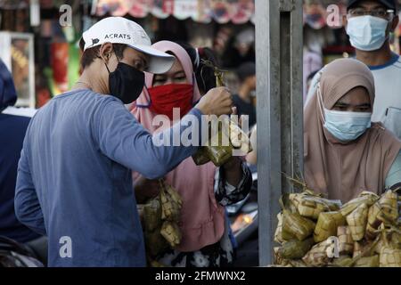 West Java, Indonesia. 12th May, 2021. People buy 'Ketupat' in Bekasi, West Java, Indonesia, on May 12, 2021. 'Ketupat', a traditional rice cake boiled in plaited coconut leaves, is often sold prior to Eid al-Fitr festival. Credit: Aditya Irawan/Xinhua/Alamy Live News Stock Photo