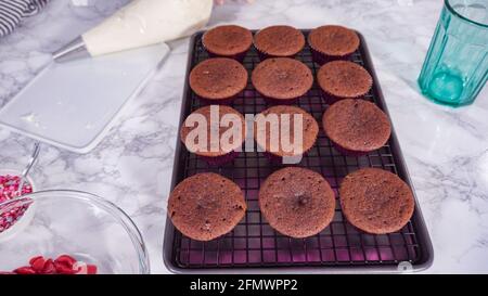 Step by step. Cooling red velvet cupcakes on a kitchen drying rack. Stock Photo