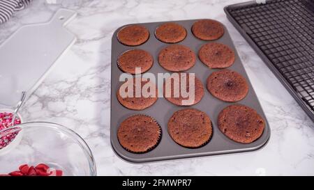 Step by step. Cooling red velvet cupcakes on a kitchen drying rack. Stock Photo