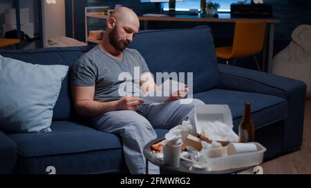 Confused frustrated stressed young man reading letter, debt notification, bad financial report, money problem, eviction notice. Shocked, worried tenant by warning document for unpaid bank bills Stock Photo