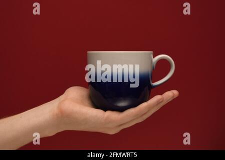 Hand holding a cup on a red background Stock Photo