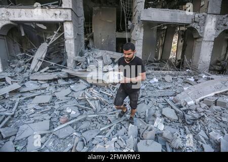 Gaza City, Palestinian Territories. 12th May, 2021. A Palestinian man walks at the rubble of the severely damaged Al-Jawhara Tower in Gaza City after it was hit by Israeli airstrikes amid the escalating flare-up of Israeli-Palestinian violence. The Health Ministry in the Hamas-run Gaza Strip said the number of Palestinians killed has risen to 35, including 12 children, while 233 people were reported injured. Credit: Mohammed Talatene/dpa/Alamy Live News Stock Photo