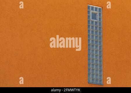 Vertical window build with glass blocks in a orange wall Stock Photo