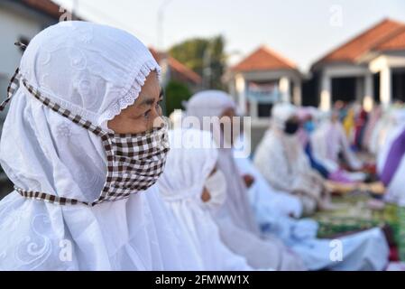 Majalengka, West Java, Indonesia - July 31, 2020 : Old muslim woman wear a mask while attend Eid Al-Adha prayers in a yard at a local mosque Stock Photo