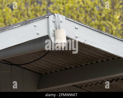 Old weathered motion detector for light attached to the front of the roof Stock Photo