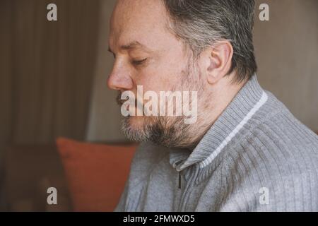 middle-aged man alone at home and looking down and depressed Stock Photo