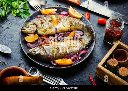 Grilled rainbow trout with lemon and onion on plate.Roasted fish Stock Photo