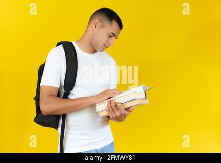 Happy handsome student reading a book isolated over yellow background. Stock Photo