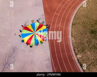 Aerial photo of a group of primary students playing with a parachute in a rural school in Qufu, Shandong, China.