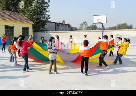Primary students playing with a parachute during a physical education class. Stock Photo