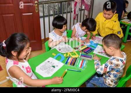 Primary students at a rural school in Xiuning, Anhui, China decorating their canvas bags. Stock Photo