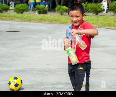 A Chinese student from Weiqiao Central Primary School in Xiuning, Anhui, China taking water bottles to his teammates. Stock Photo