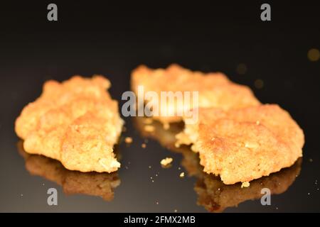 One fragrant crunchy cereal broken cookie, close-up, against a black background. Stock Photo