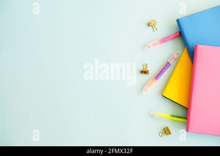 Feminine set of school supplies, yellow pink cover, blank sheet open notebook, pencil sharpener, colorful pen, binders, stickers & eraser, blue wooden Stock Photo