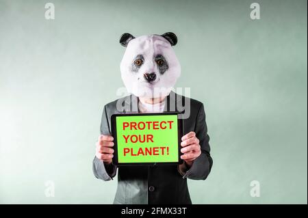 Man dressed as a panda bear head and holding a tablet with the message PROTECT YOUR PLANET Stock Photo
