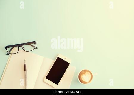 Minimalistic flat lay composition of black & white laptop computer keyboard, cell phone gadget, cup of coffee & folded glasses on textured wooden desk Stock Photo