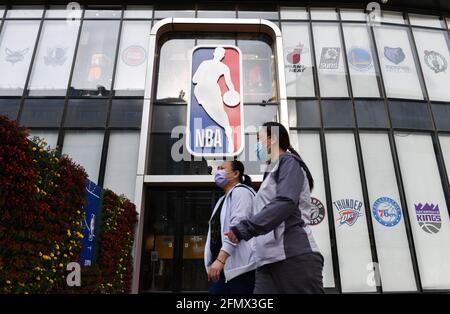 Beijing, China. 10th May, 2021. Women walk past the NBA logo and store on Wangfujing Street in Beijing. Credit: SOPA Images Limited/Alamy Live News Stock Photo