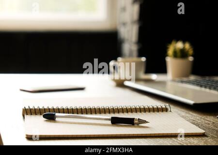 Creative workspace of a blogger. White blank screen laptop computer & smartphone on wooden table in loft style office with black brick walls. Designer Stock Photo