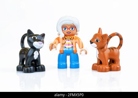 KHARKIV, UKRAINE - March 29th, 2020: Toy old lady with two toy cats, plastic toys, pre-school education theme, isolated on white Stock Photo