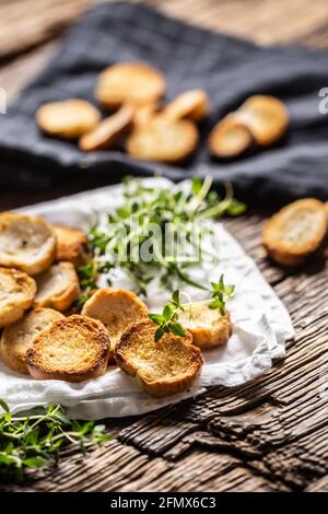 Small round salty mini bake rolls with lovely crunchy flavour and goldish colour made of baked bread and served in the paper or dish cloth with thyme. Stock Photo