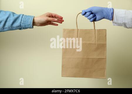 Hand in glove give a paper bag to woman Stock Photo