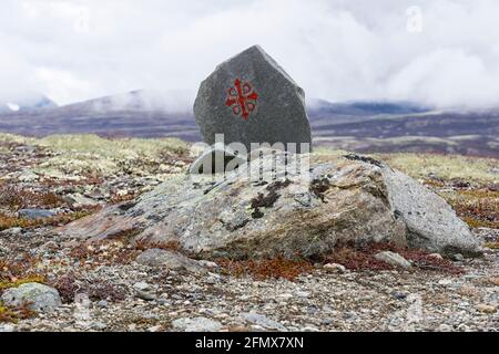 Route marker of Pilegrimlsleden in late autumn against dark clouds.Pilgrim's Route, Dombås, Dovre Nationalpark, Innlandet, Norway Stock Photo