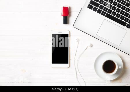 Minimalistic flat lay composition, black & white laptop computer keyboard, cell phone gadget, coffee cup, ail polish & earphones on textured wooden de Stock Photo