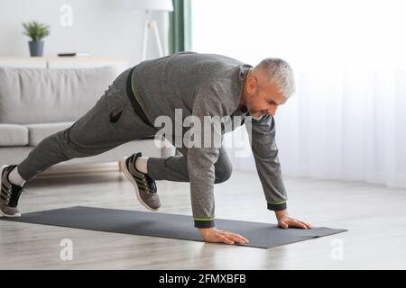 Athletic bearded senior man doing exercises at home Stock Photo