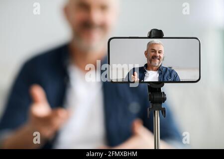 Mobile phone screen with cheerful senior man blogger Stock Photo