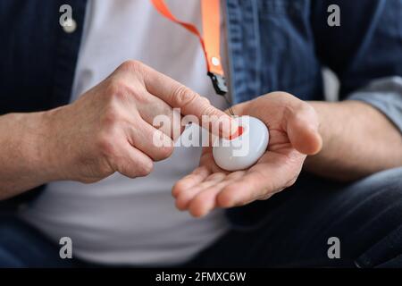 Hand pushing panic button on emergency equipment for elderly people Stock Photo