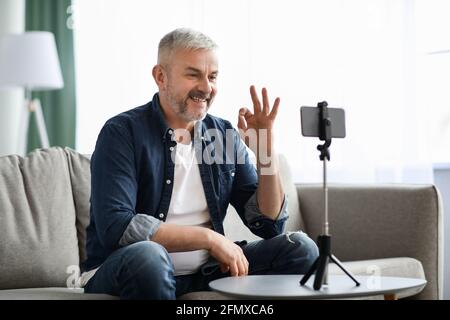Smiling senior man vlogger broadcasting from home Stock Photo