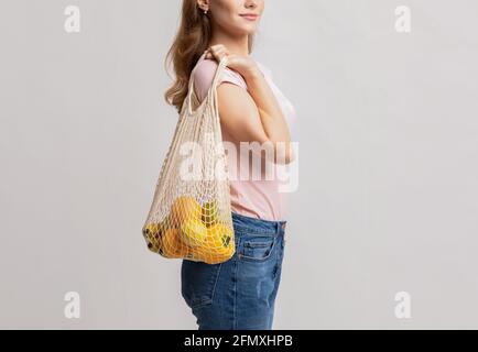 Eco Living. Millennial Female Carrying Vegetables And Fruits In Reusable Mesh Bag Stock Photo