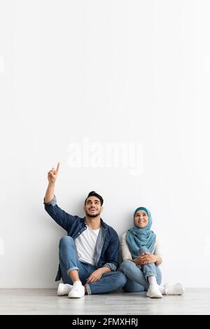Cute muslim couple looking at empty space on white Stock Photo