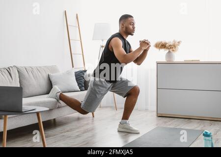Sporty Black Guy Doing Single-Leg Squats Exercising Online At Home Stock Photo