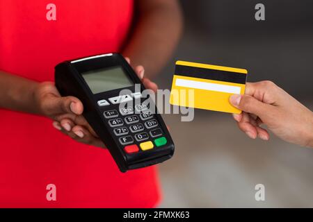 Black delivery man in uniform holding POS machine for payment Stock Photo