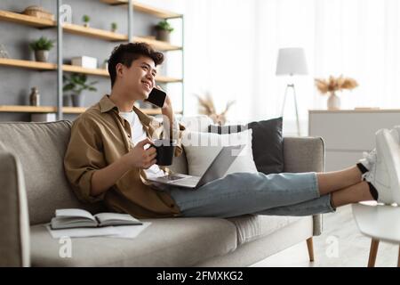 Smiling asian man working and talking on phone at home Stock Photo