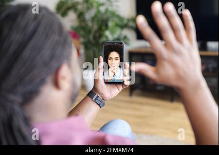African-American man using smartphone for video connect with female colleague, black guy holding phone with charming biracial woman on the screen, has video call with girlfriend Stock Photo