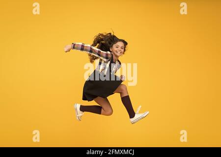 Fun and jump. Happy childrens day. Jump concept. Break into. Feel inner energy. Girl with long hair jumping on yellow background. Carefree kid summer Stock Photo