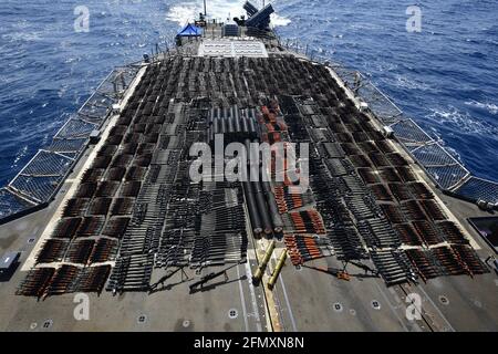 The U.S. Navy Ticonderoga-class guided-missile cruiser USS Monterey, displays thousands of illicit weapons on the rear deck, confiscated from smugglers in international waters May 6-7 in the North Arabian Sea. Stock Photo